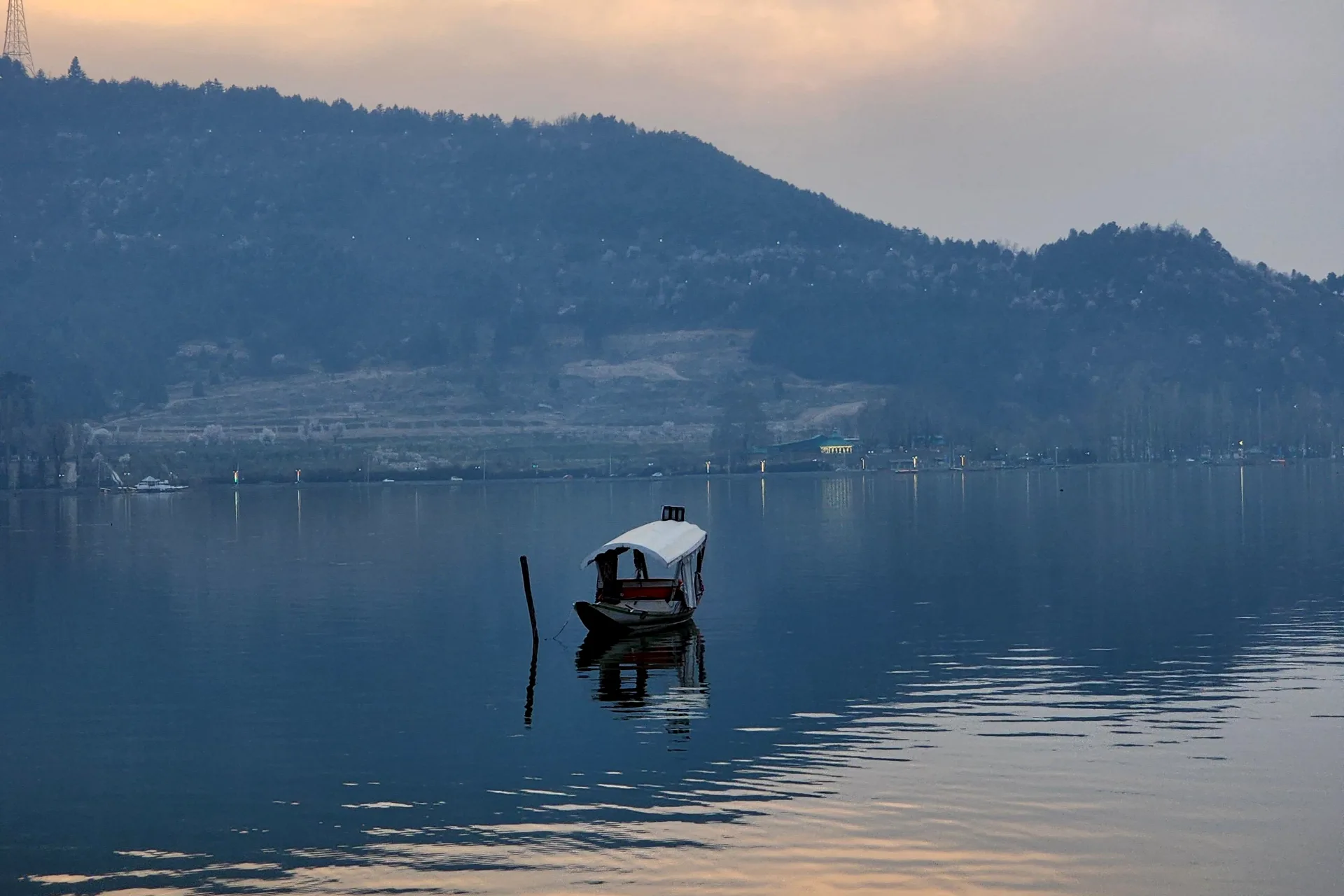A shikara on Dal Lake at dusk below the Zabarwan hills