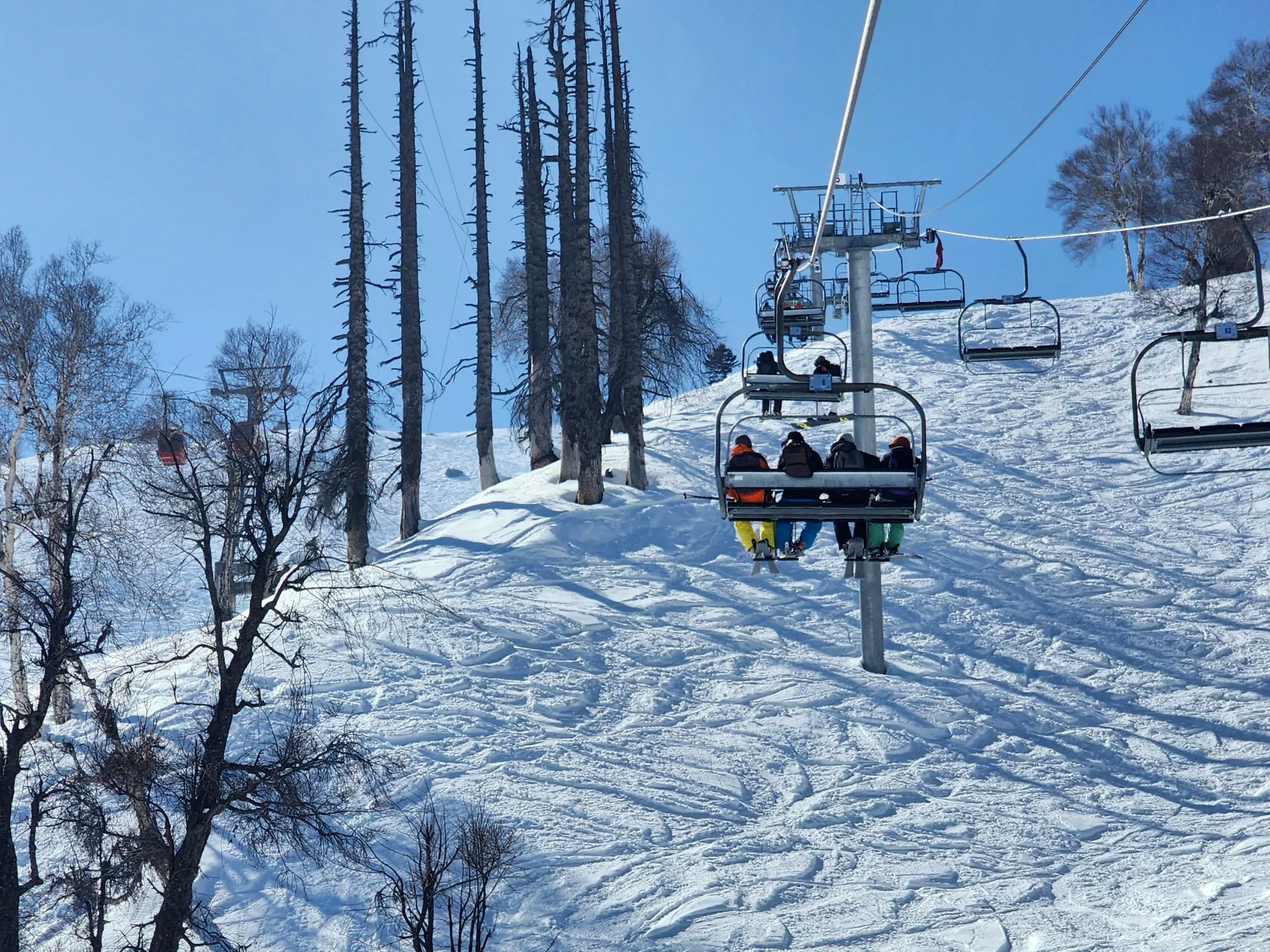 Skiers riding the chairlift above a Gulmarg slope